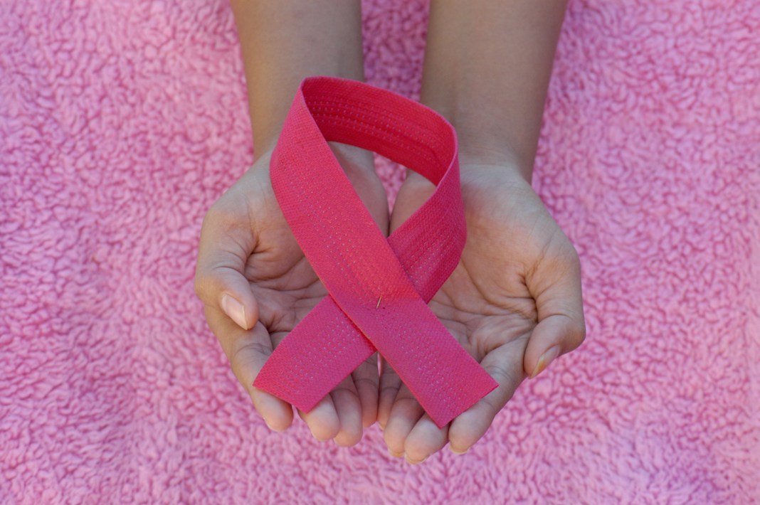 Hands holding a pink awareness ribbon for World Cancer Day